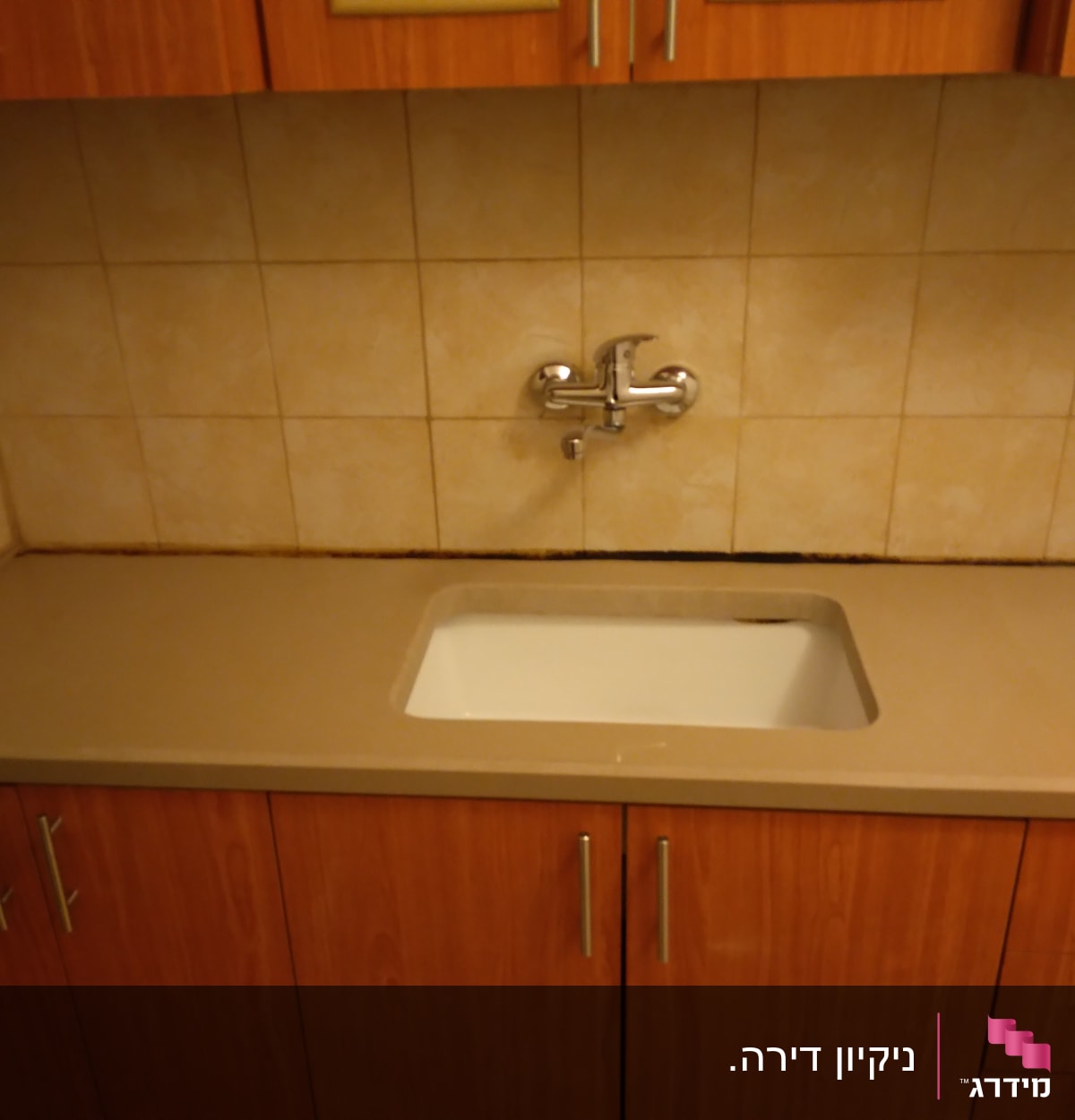 כיור מטבח עם ברז על רקע אריחים